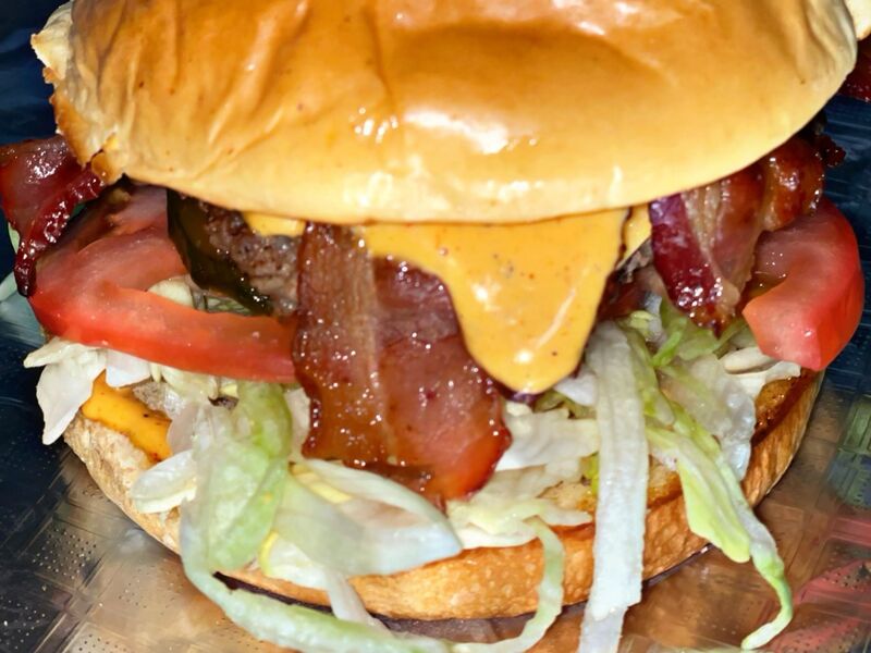 A bacon cheeseburger with lettuce and tomato