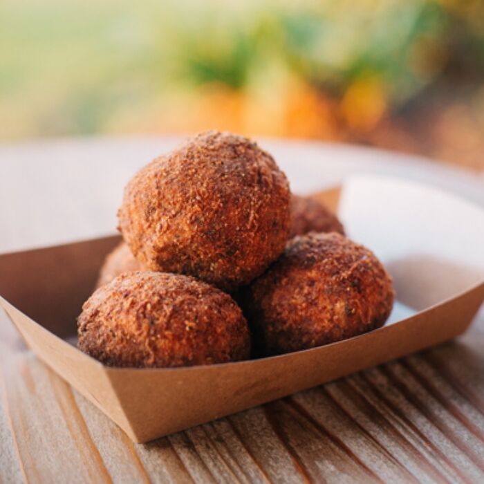Four fried boudin balls in a paper boat